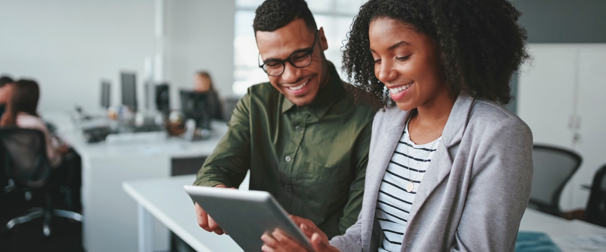Smiling young businessman and businesswoman working online with a digital tablet