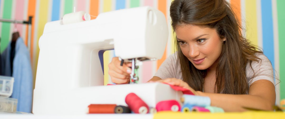 Woman concentrates on sewing fabric using a sewing machine