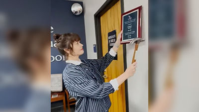 graduate school employee hanging up a plaque on the wall