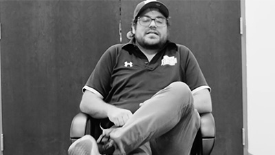 UNF employee sitting in a chair with his legs crossed