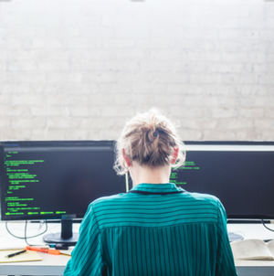 women in front of two computer screens