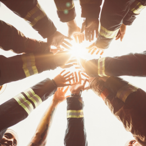 firefighters putting their hands in a circle