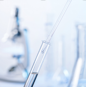 dropper in a test tube with microscope and flask in background