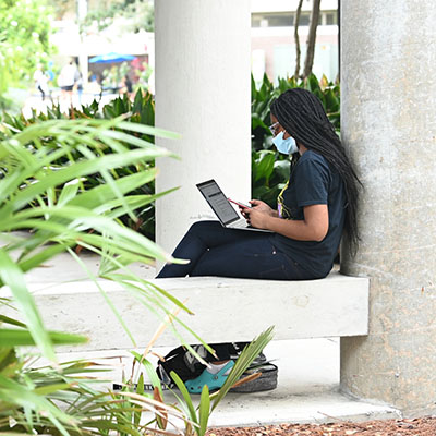student sitting on a wall studying