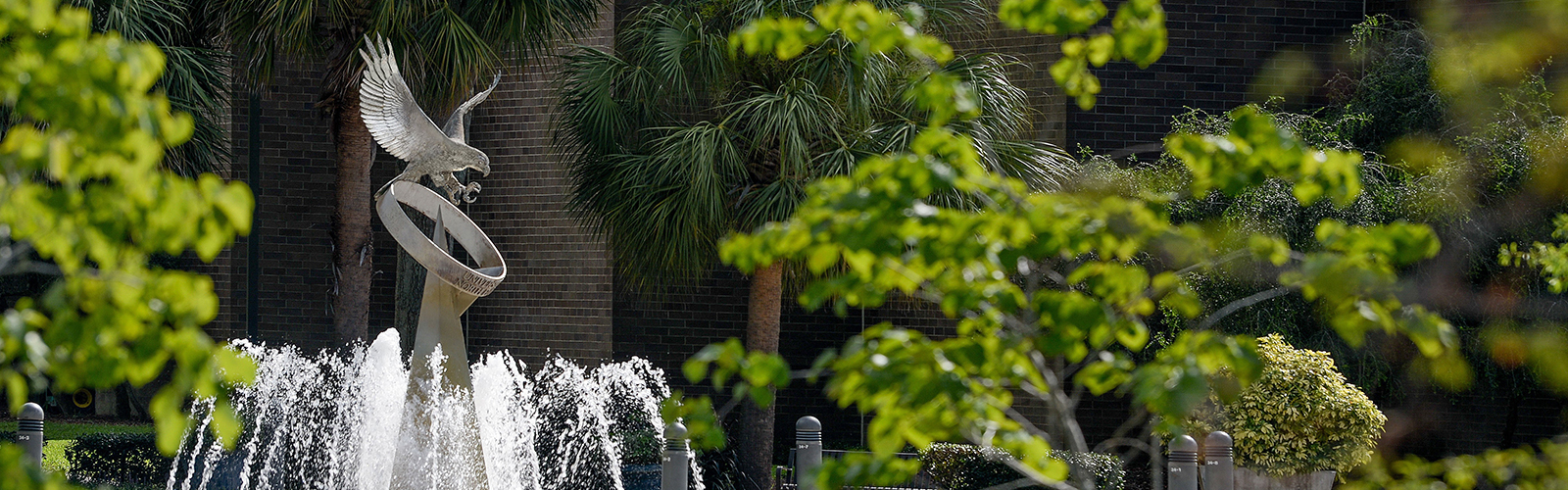 Osprey statue and fountain surrounded by trees and other greenery