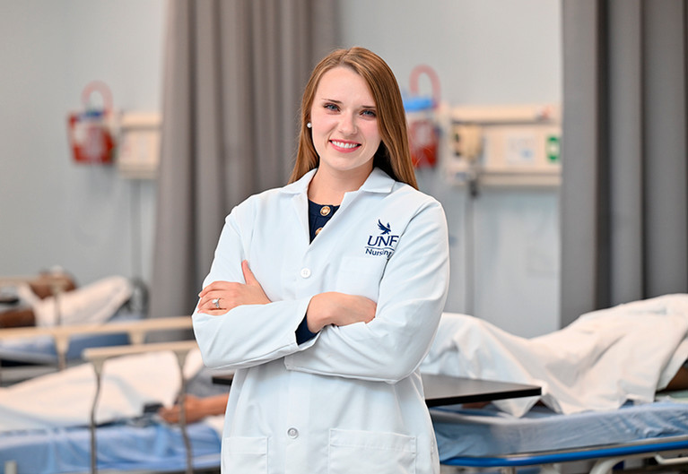 UNF nursing student wearing a nursing white lab coat in a hospital