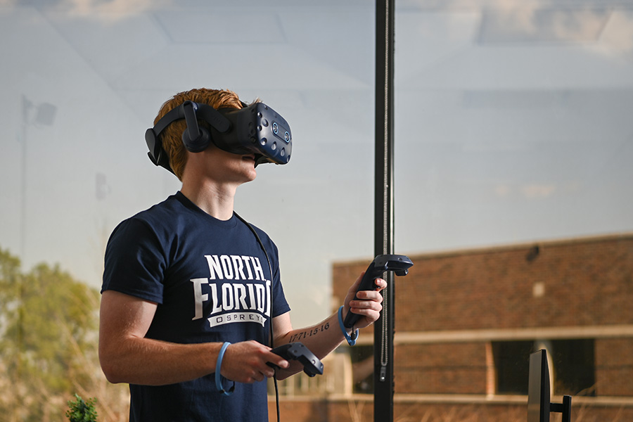 UNF student wearing a VR headset and holding VR controllers