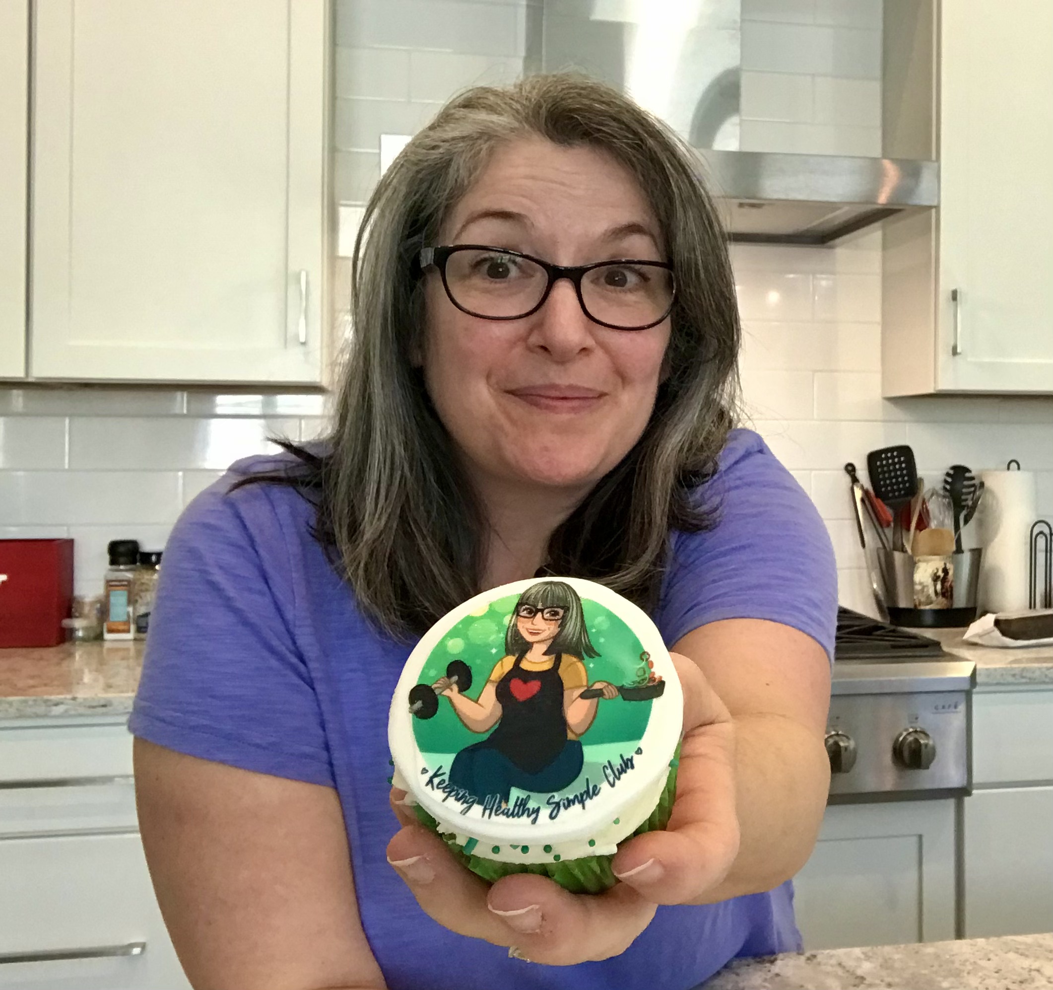 Alexa Lewis holding a cupcake that has her business logo on it
