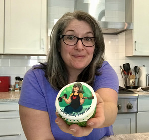 Alexa Lewis holding a cupcake that has her business logo on it
