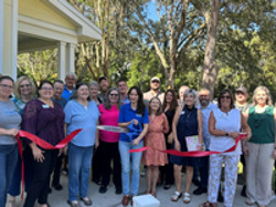 group of people around business owner doing a ribbon cutting for grand opening