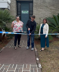 people doing a ribbon cutting in front of their business 