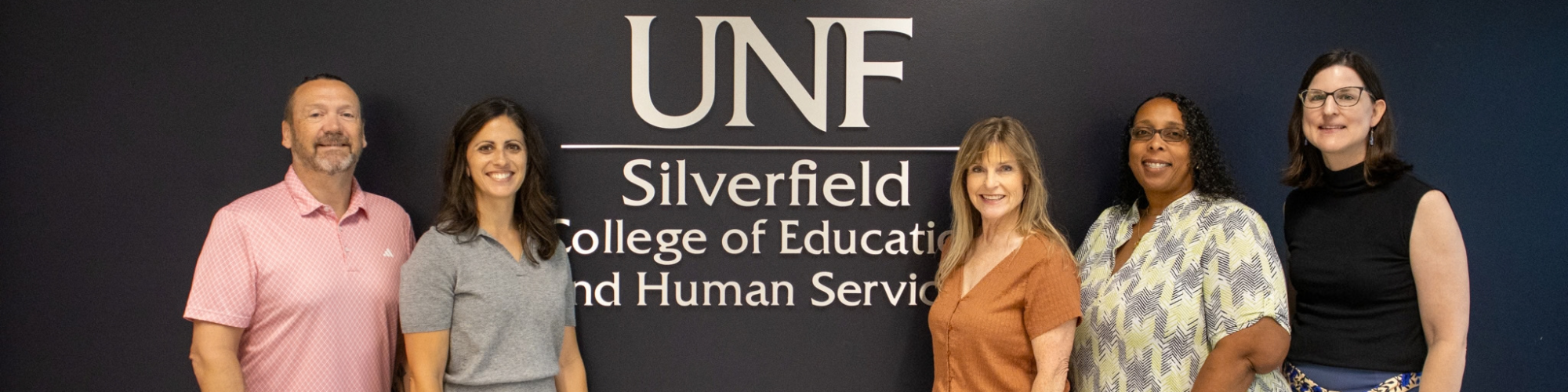 EC Faculty in front of Silverfield sign