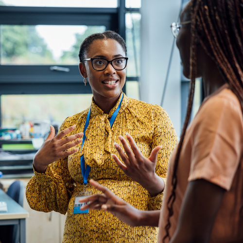 Female educational professional conversing with a high school student in a classroom