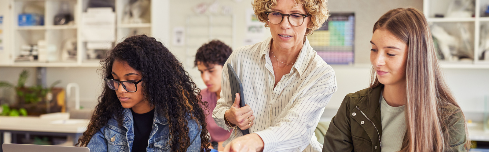 Highschool teacher instructing two students in a classroom 