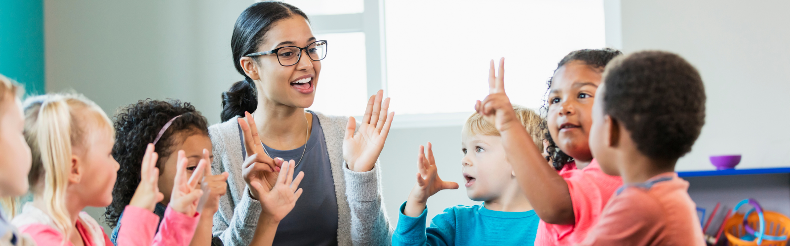 Teacher sits with a small group of preschool students.