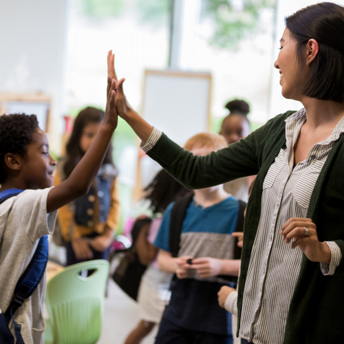 Teacher high-fiving a student and smiling