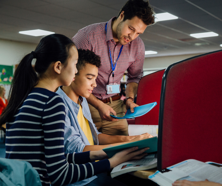 Teacher helps a group of students studying in the library.