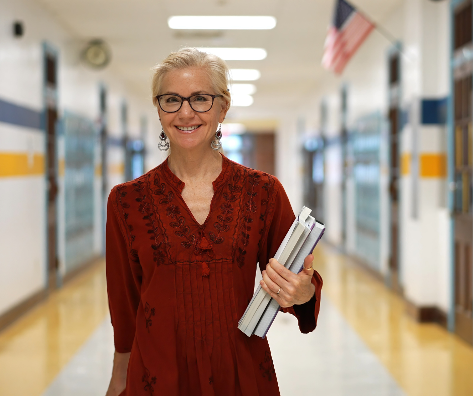 A teacher stands in the hallway of a school.