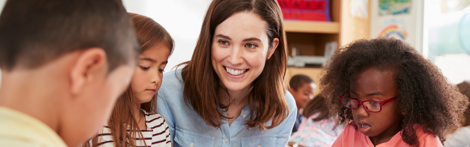 A teacher smiles while working with a small group of students.