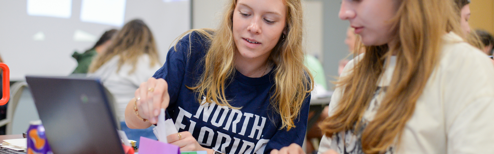 Female student wearing UNF Shirt working in classroom