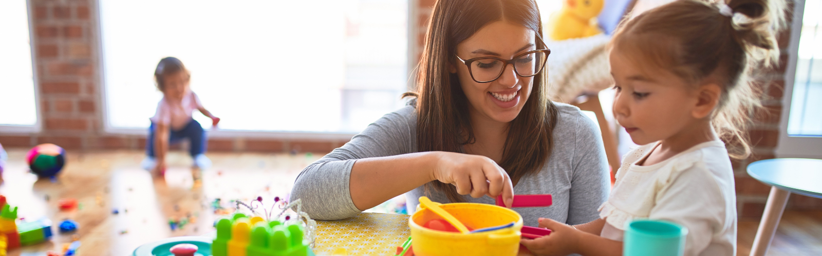 A teacher plays with a young student in a preschool classroom.