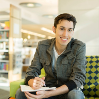 A college students smiles while studying in the library.