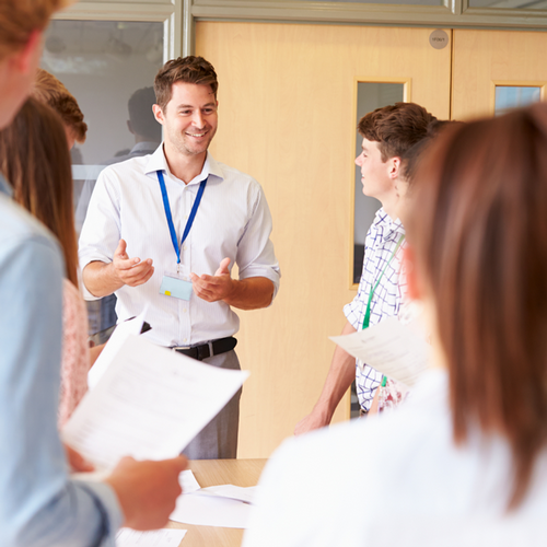 Education professional interacting with high school students in a classroom 