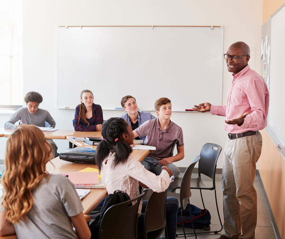 A social studies teacher stands in front a class of high school students.