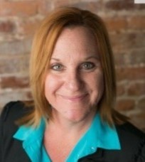 Jennifer Kirouac headshot in front of brick wall