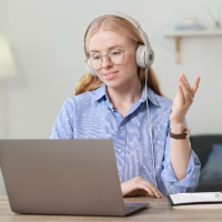 White woman with headphone while in a virtual meeting on computer