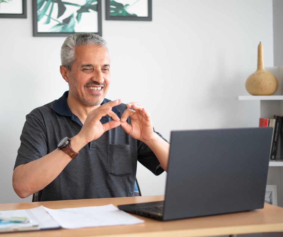 Man uses American Sign Language on a video call on his laptop.