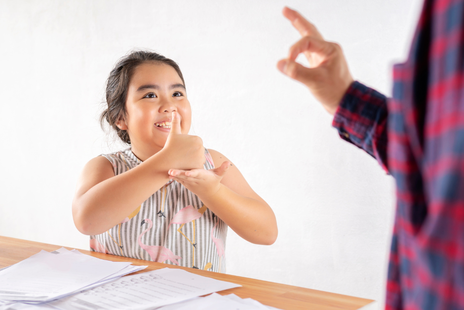Young girl signing to another individual in classrooms setting