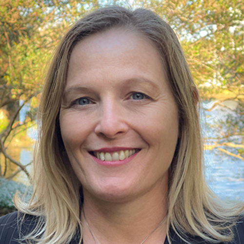 Dr. Caroline Guardino smiles while standing outside with trees in the background.