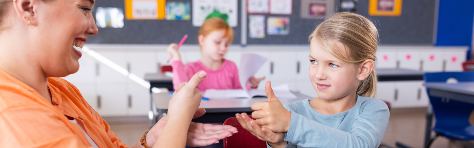 A student and teacher communicate using ASL in a classroom.