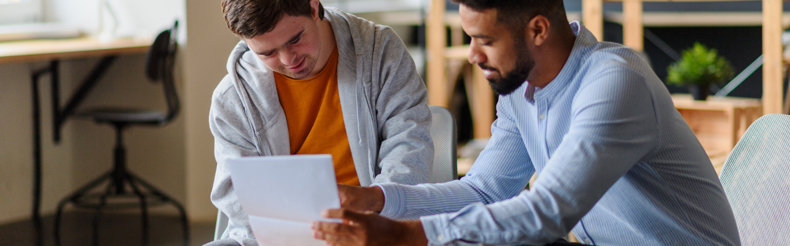 Two young adult males looking at paperwork in a modern workplace setting