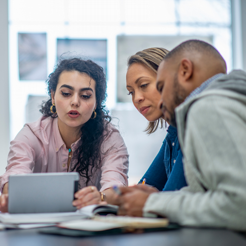Three individuals working on a project and looking at a iPad