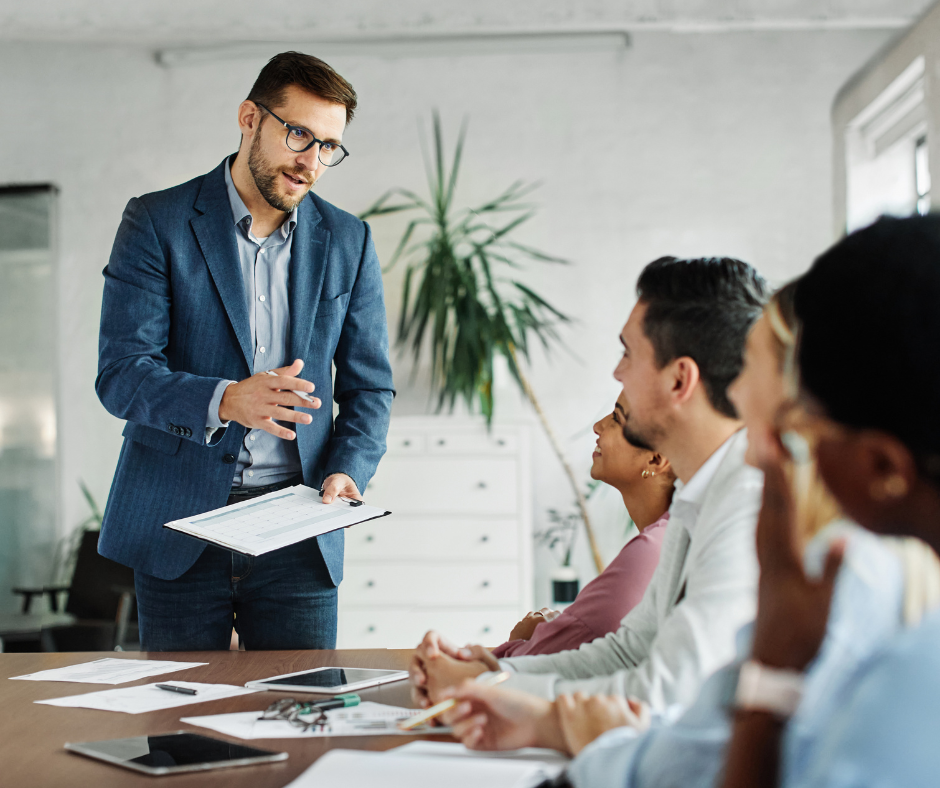 An administrator talks to a group of colleagues during a meeting.