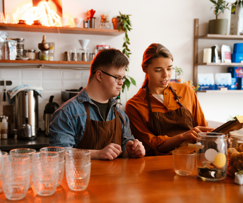 A young man and a young woman working at a coffee shop register