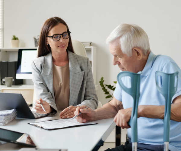 A professional assisting an elderly man with paperwork 