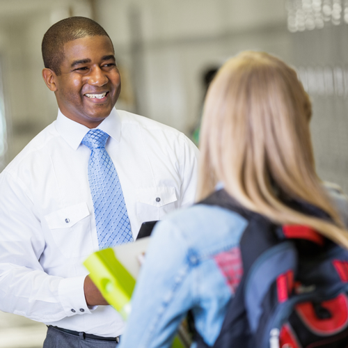 Education professional smiling at student in hallway