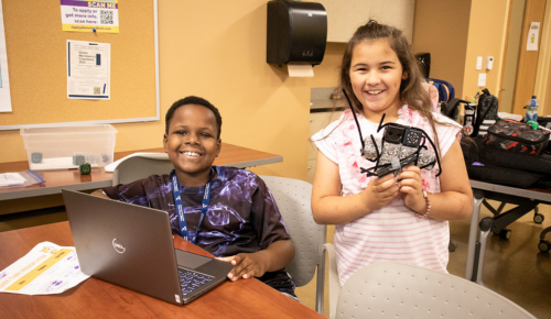 Two students work together to program a robot using a laptop.