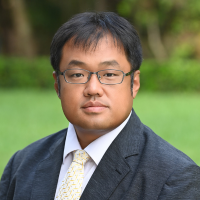 Headshot of Dr. Choi in suit with greenery background