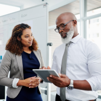 Male mentor holding an Ipad next to female mentee
