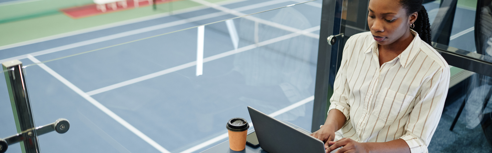 Female student typing on computer near tennis court