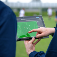 A hand touching a IPAD displaying a football field