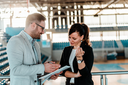Two professionals having a meeting near a tennis court 