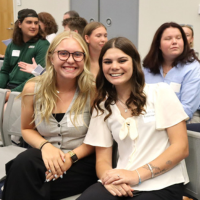 Two female UNF students sitting and smiling in professional attire
