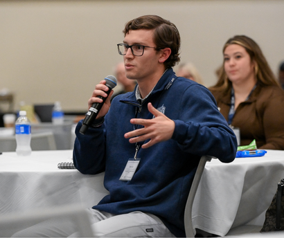 Student talking into microphone at a conference
