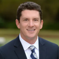 Headshot of Nick Morrow smiling and wearing a blue suit and tie