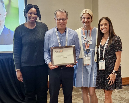 Steve Dittmore holding up award received at AERA Conference 2026